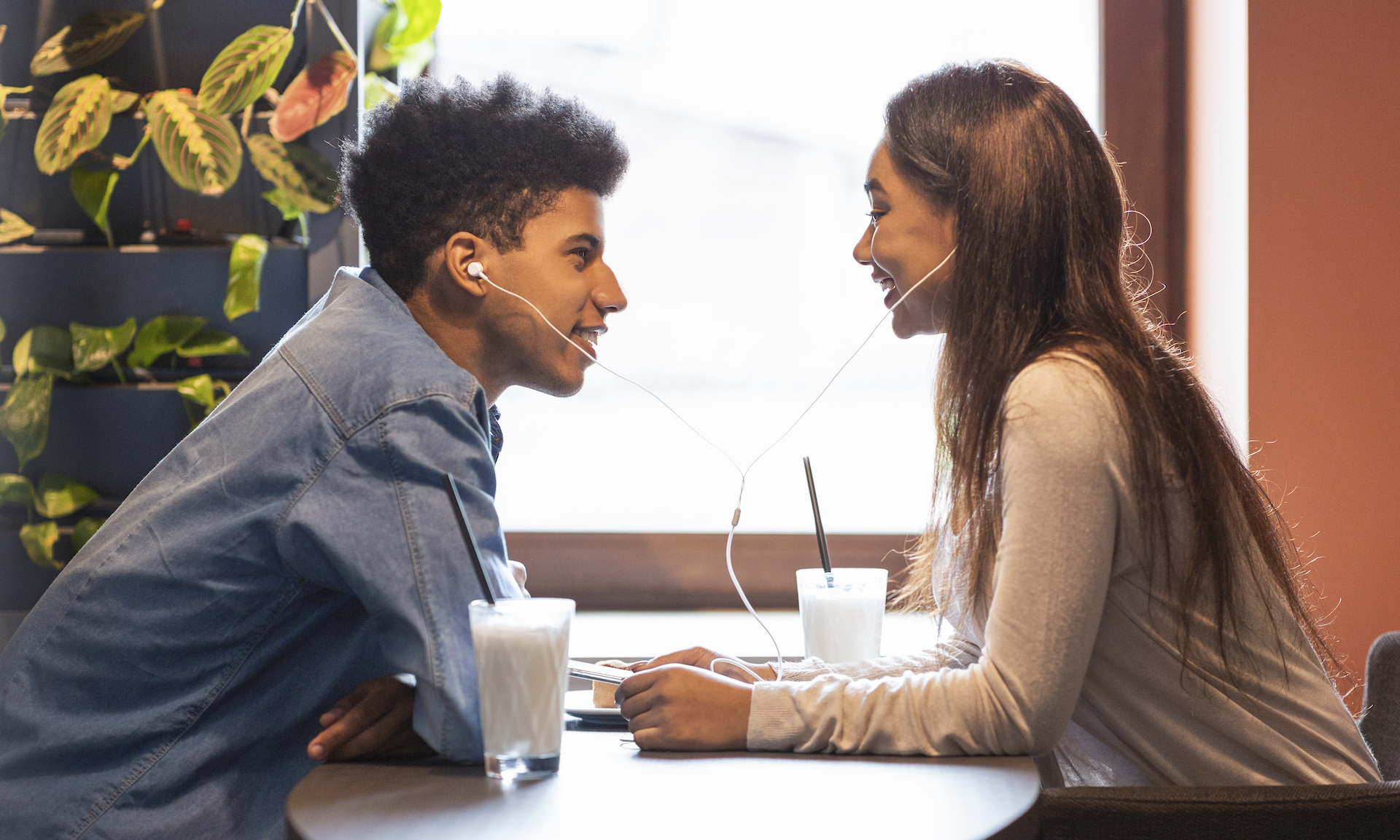 Young couple laying on their backs on pavement looking up at camera with smiles.